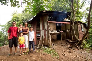 A Nicaraguan family stands by their dilapidated housing, and the mother smiles about their new housing with Giveback Homes. (CONTRIBUTED) 