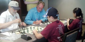 Hitachi Chess Team members Russ Freeman, from top left, and Jack Harmsen prepare to face Madison City Chess League players Michael Guthrie and Constance Wang. (CONTRIBUTED)