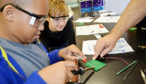 Ashton Bradley solders a circuit board as fellow seventh-grader A. J. Fredette inspects his work during robotics class at Liberty Middle School. (CONTRIBUTED) 