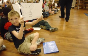 Fourth-grader David Lockhart proudly shows his own drawing during illustrator Michael White's presentation at Madison Elementary School. (RECORD PHOTO/GREGG PARKER) 