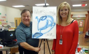 Professional illustrator Michael White shows his drawing of the Madison Elementary School mascot, a hornet, to media specialist Shanna Edgar. (RECORD PHOTO/GREGG PARKER) 