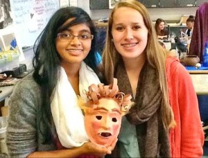 Meenu Bhooshanan, at left, and Becca Fraley show the Greek mask that they designed for the collaboration among Latin, drama and art classes in the Patriot Project. (CONTRIBUTED) 