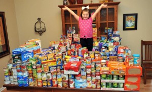Kendall Preston is dwarfed by huge stacks of canned and boxed food that she collected instead of asking for birthday presents. (PHOTO / CRISTEN SMITH/FLASHLIGHTS & FIREFLIES PHOTOGRAPHY)
