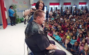 As students and teachers cheer, Heritage Principal Dr. Georgina Nelson shaves Coach Rob Carter's head and beard. (Record photo / Gregg Parker) 