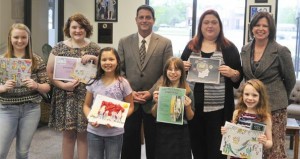 For National Library Week, Madison Public Library conducted the "Where Does Reading Take You?" poster contest. Winners and presenters at City Council's April 13 meeting were Emma Wade, from left, Evi Jones, Jyoti Amrhein, Mayor Troy Trulock, Lilly Butler, Shania Burrows, Emily Adams and library branch manager Sarah Sledge. (RECORD PHOTO/NICK SELLERS) 
