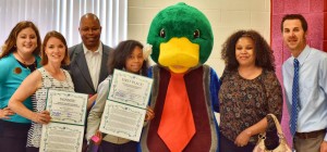 Kloe Howard won the essay contest sponsored by Homewood Suites by Hilton - Village of Providence. Also shown are Ashley Polesak, from left, with Homewood Suites, teacher Robin McDonnell, Mr. Howard, mascot Lewis the Duck, Mrs. Howard and Harvest principal Brett Chapman. (CONTRIBUTED) 
