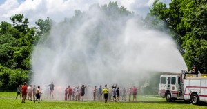 Incoming sixth-graders from Horizon and Heritage elementary schools and St. John the Baptist Catholic School get relief from the heat in a massive water spray from Madison firefighters during Kids Camp, sponsored by Madison Police Foundation and Madison Police Department. (CONTRIBUTED) 