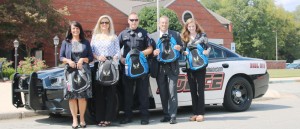 Officer Aubrey Walls and Lt. Wayne Kamus with Madison Police Department, at center, receive My Guardian Angel backpacks from Vicki Pruitt, from left, Lori Warren and Anna Faulk with Alabama Court Reporting. (CONTRIBUTED) 