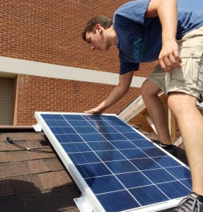 A Construction Academy student at James Clemens High School installs a solar panel on the 'tiny house,' a collaborative effort among school departments and business partners. (CONTRIBUTED) 