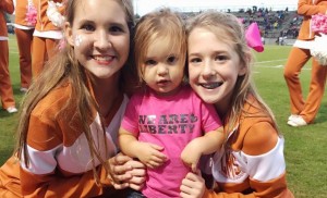 Liberty Middle School cheerleaders Avery Jones, at left, and Kate Byrne, at right, encourage little Liberty Lions fan Lilly Merrill, who is wearing a "We are Liberty" T-shirt. (CONTRIBUTED) 