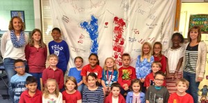 Amy William's third-grade class surrounds their banner for Paris that they will ship to a school affected by terrorist attacks. CONTRIBUTED