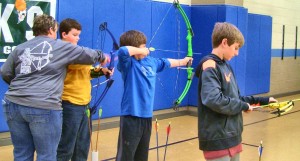 Mill Creek archery coach Martha Pritchard helps fourth-grader Will Bagwell from Columbia Elementary School set his bow in his first archery tournament. Columbia students Mikel Booth and Brandon Booth also competed. CONTRIBUTED