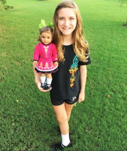 Ella Dickerson takes a stance for Irish dance and holds her American Girl doll, also costumed for Irish dance. CONTRIBUTED